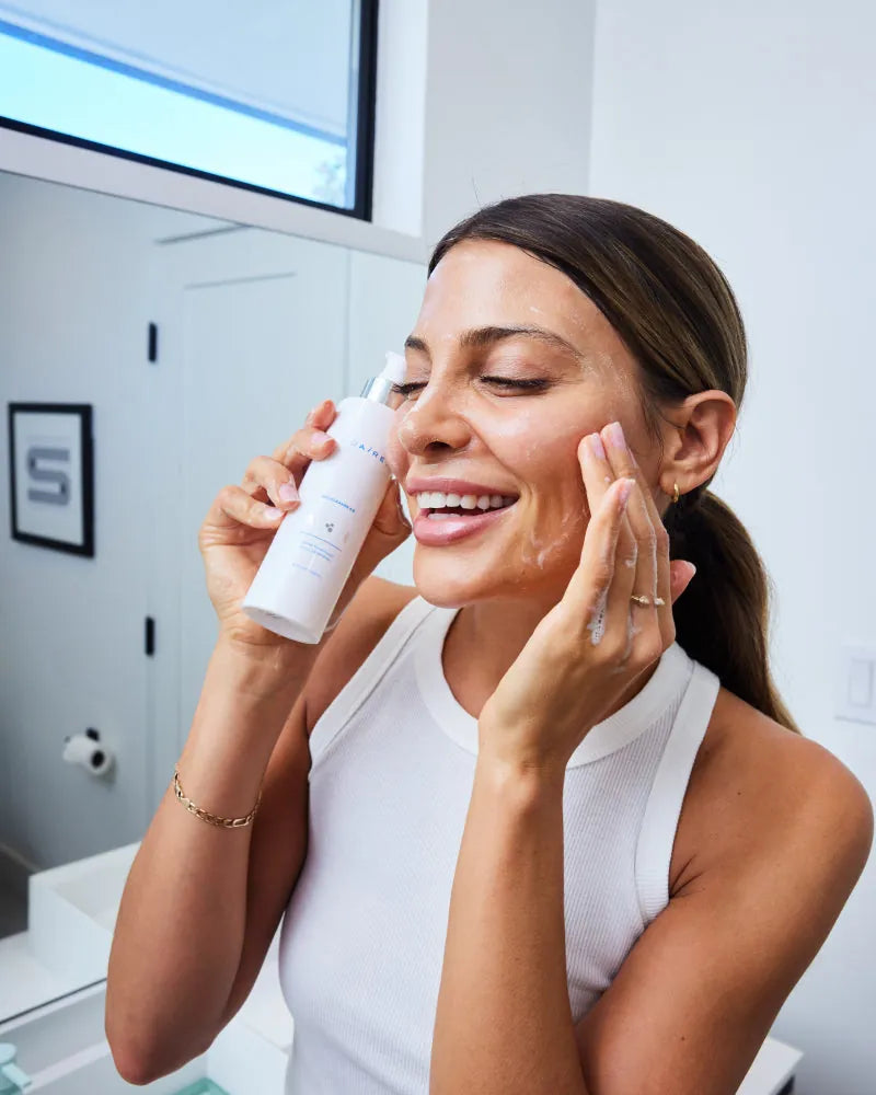 Smiling woman applying Bio-Cleanse 5.5  Face wash lather to face in br
