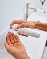 Person dispensing MDAiRE Bio-Cleanse 5.5 Face wash gel into palm over bathroom sink gallery position 1