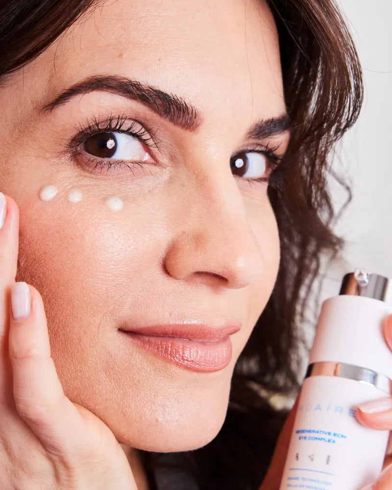 Woman applying eye cream from Skincare Essentials Bundle under eye hig