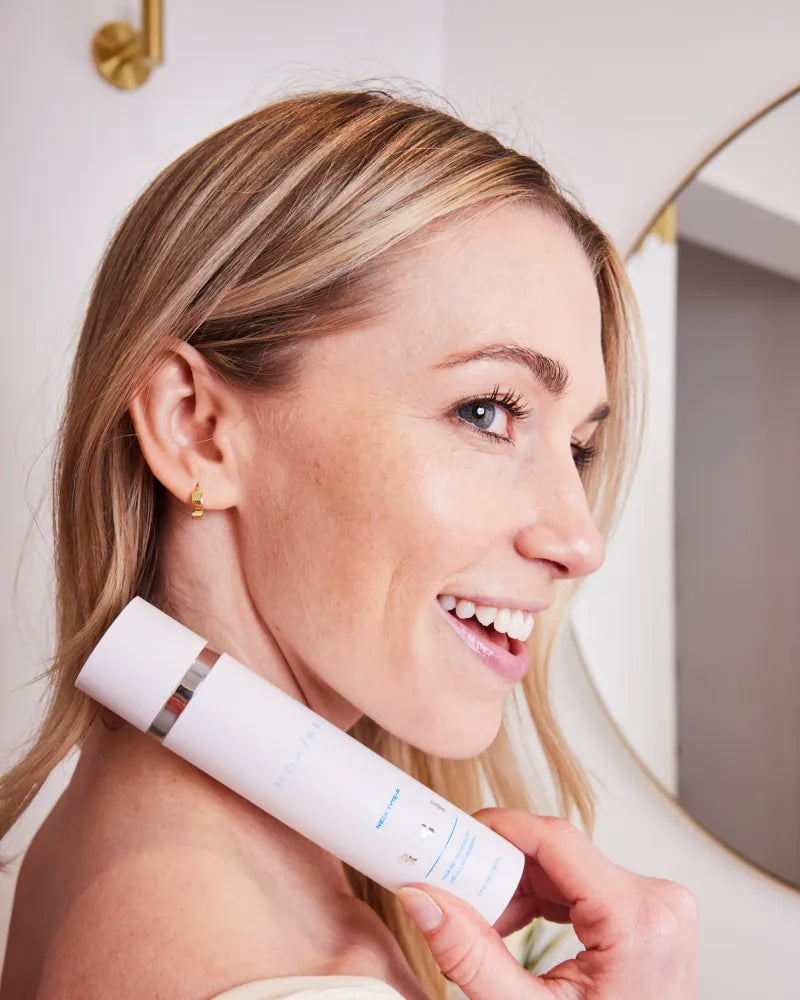 Smiling woman holding Neck Tyte-R moisturizer close to her neck with w
