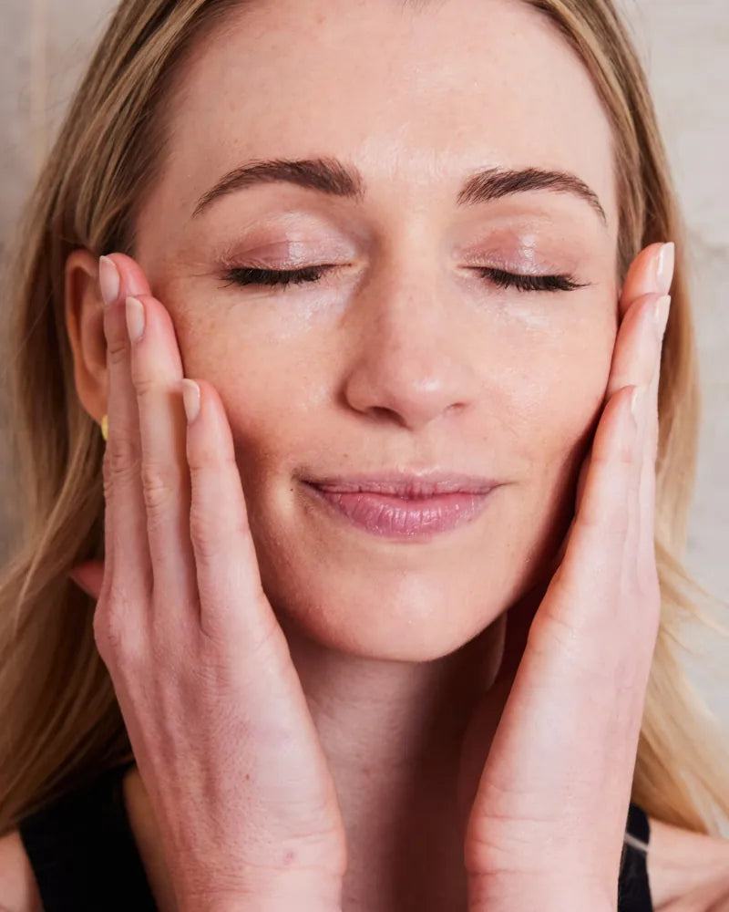 Woman gently touching her face with glowing skin, embracing Healthy Sk