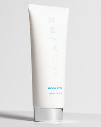 Body Glow Duo Body Tyte tube with silver cap standing upright on pale gray background gallery position 1